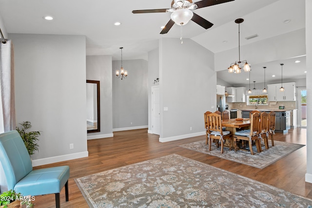 dining area featuring ceiling fan with notable chandelier, hardwood / wood-style floors, and high vaulted ceiling