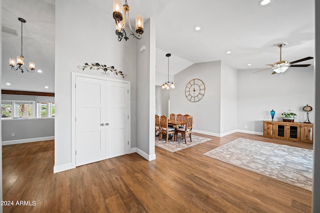 foyer entrance featuring wood-type flooring, ceiling fan with notable chandelier, and high vaulted ceiling