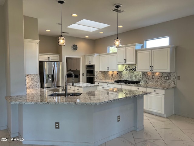 kitchen featuring sink, a skylight, stainless steel appliances, and hanging light fixtures