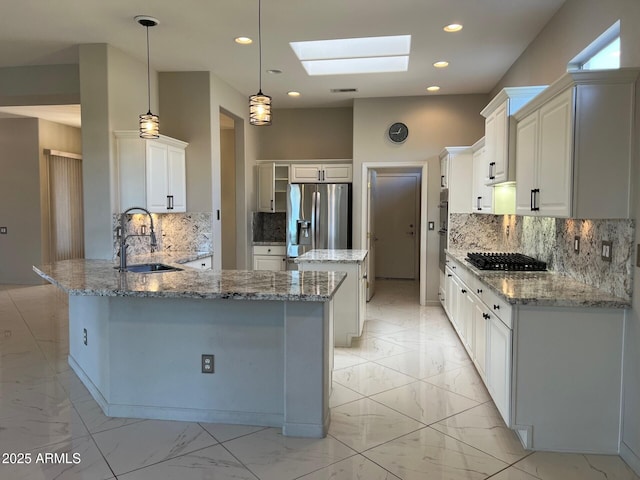 kitchen featuring pendant lighting, sink, a skylight, stainless steel fridge with ice dispenser, and kitchen peninsula