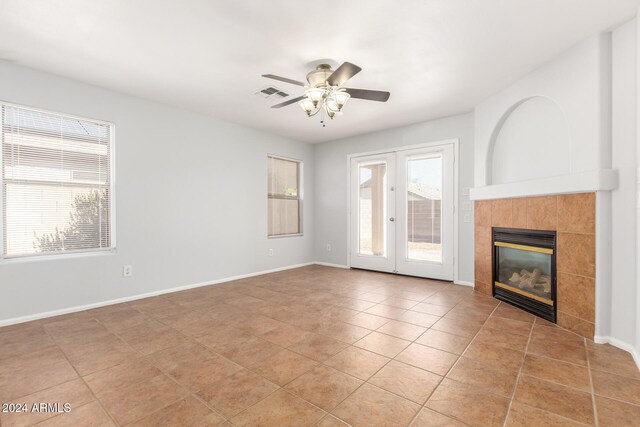 unfurnished living room with a tile fireplace, french doors, ceiling fan, and light tile patterned flooring