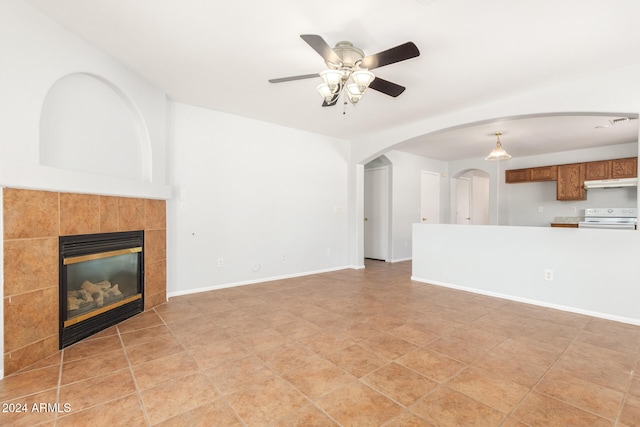 unfurnished living room with ceiling fan and a tiled fireplace