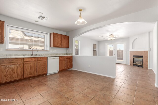 kitchen with white dishwasher, ceiling fan, light tile patterned floors, a fireplace, and hanging light fixtures