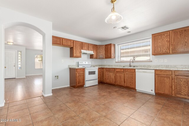 kitchen with white appliances, light hardwood / wood-style floors, hanging light fixtures, and sink