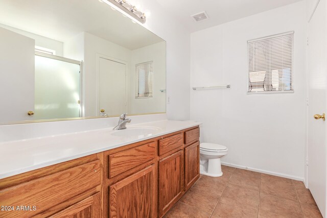 bathroom with toilet, vanity, and tile patterned floors