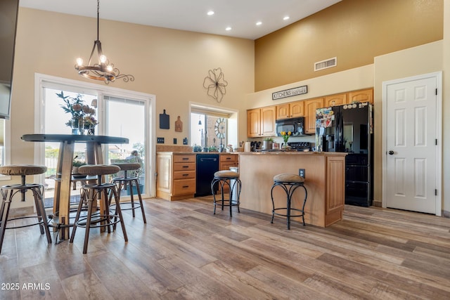 1437 E Glenhaven Dr, Phoenix, AZ 85048 - kitchen featuring black appliances, a kitchen island, a high ceiling, a chandelier, and light wood finished floors