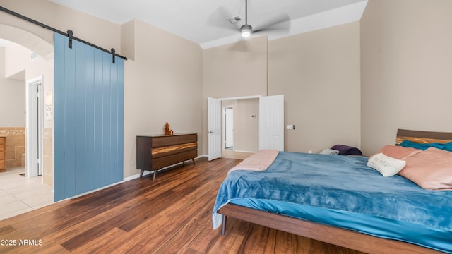 116 E Mountain Sky Ave, Phoenix, AZ 85048 - bedroom featuring a barn door, a high ceiling, wood finished floors, arched walkways, and ceiling fan