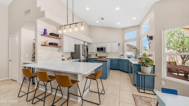 116 E Mountain Sky Ave, Phoenix, AZ 85048 - kitchen with blue cabinets, stainless steel appliances, high vaulted ceiling, open shelves, and tasteful backsplash