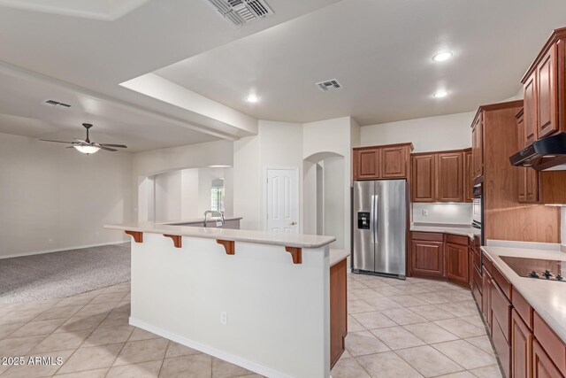 13007 W Tuckey Ct, Glendale, AZ 85307 - kitchen featuring stainless steel fridge with ice dispenser, arched walkways, black electric cooktop, a breakfast bar area, and light countertops