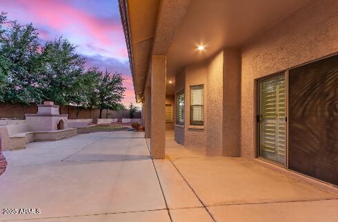 13007 W Tuckey Ct, Glendale, AZ 85307 - patio terrace at dusk with an outdoor fireplace and fence
