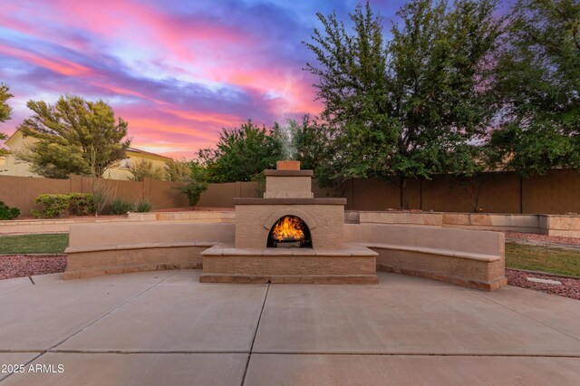 13007 W Tuckey Ct, Glendale, AZ 85307 - patio terrace at dusk with a warm lit fireplace and a fenced backyard