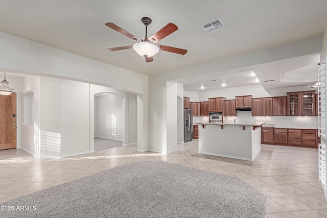 13007 W Tuckey Ct, Glendale, AZ 85307 - unfurnished living room with arched walkways, light tile patterned floors, ceiling fan, and baseboards