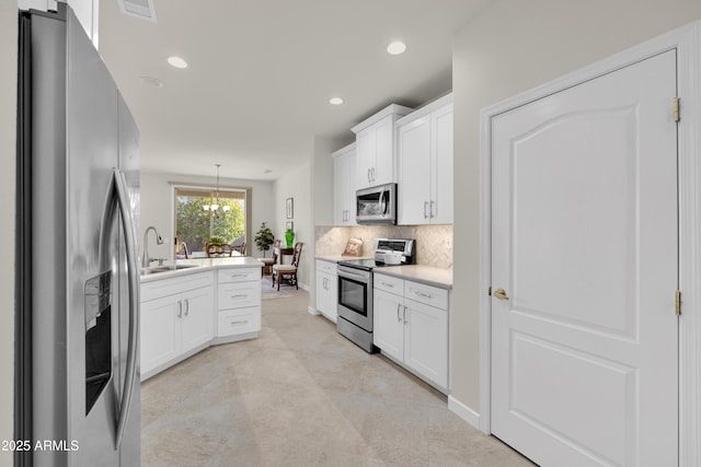 kitchen featuring sink, decorative light fixtures, white cabinets, stainless steel appliances, and backsplash