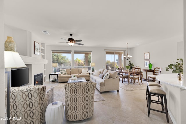 living room with ceiling fan with notable chandelier