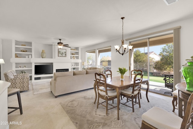 dining area featuring ceiling fan with notable chandelier and built in features