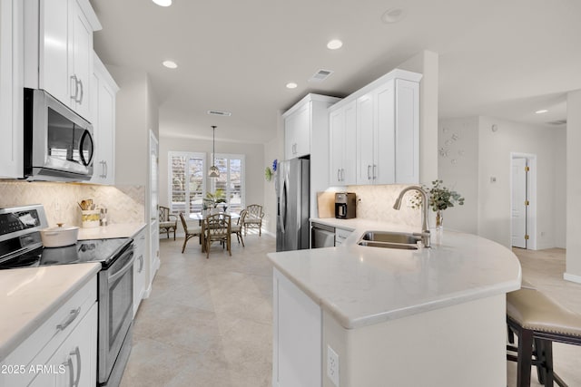 kitchen featuring hanging light fixtures, white cabinetry, appliances with stainless steel finishes, and sink