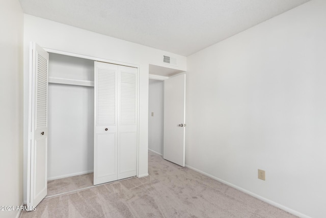 unfurnished bedroom with light colored carpet and a closet