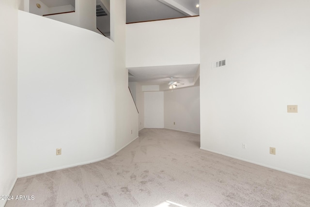 interior space featuring ceiling fan, a towering ceiling, and light colored carpet