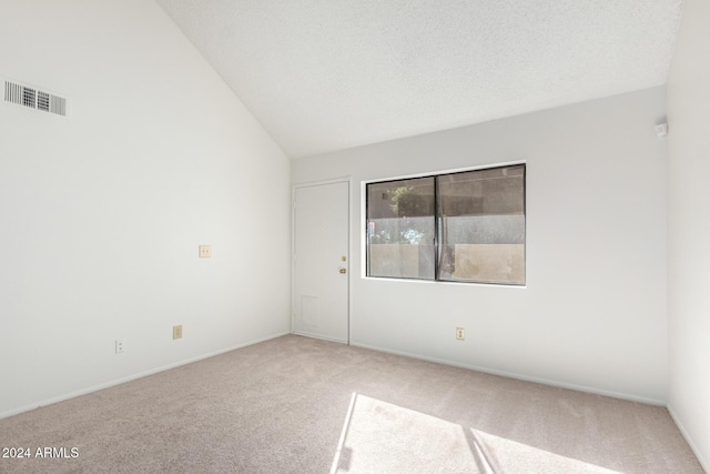 carpeted spare room featuring a textured ceiling and vaulted ceiling