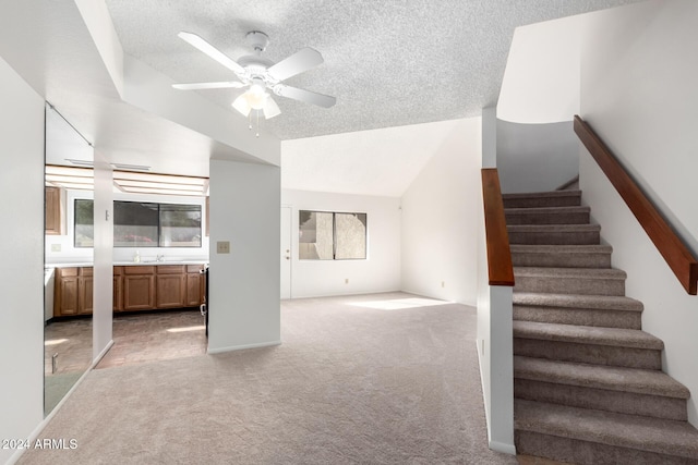 interior space with a textured ceiling, ceiling fan, lofted ceiling, and light carpet