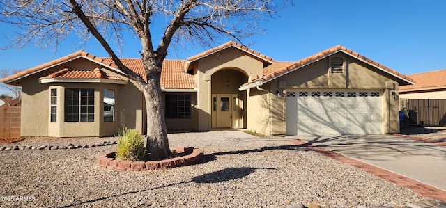 mediterranean / spanish-style house featuring fence, stucco siding, concrete driveway, a garage, and a tile roof