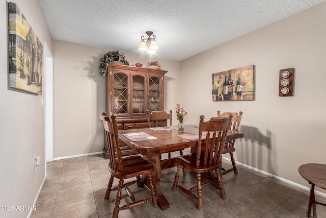 dining room with tile patterned floors, an inviting chandelier, and a textured ceiling