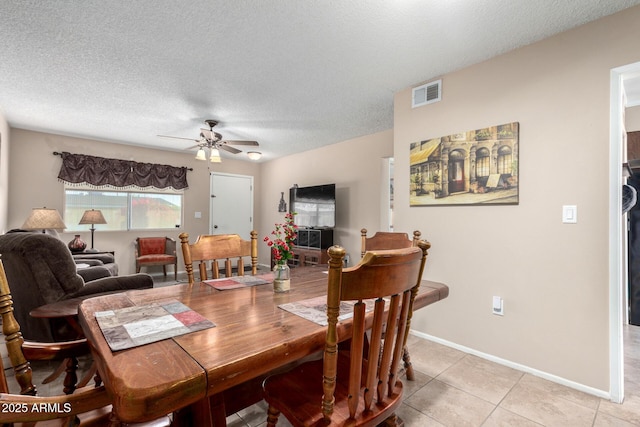 dining area with ceiling fan, a textured ceiling, and light tile patterned flooring