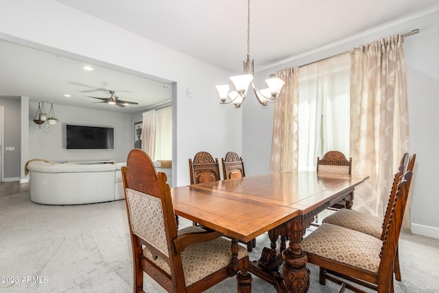 carpeted dining space with ceiling fan with notable chandelier and a wealth of natural light