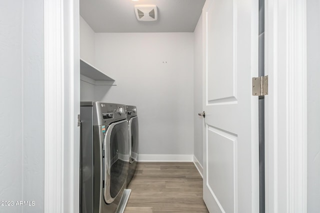 laundry room with washing machine and dryer and light wood-type flooring