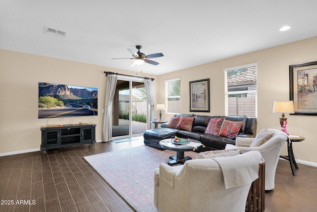 living area with dark wood-type flooring, a ceiling fan, visible vents, and baseboards