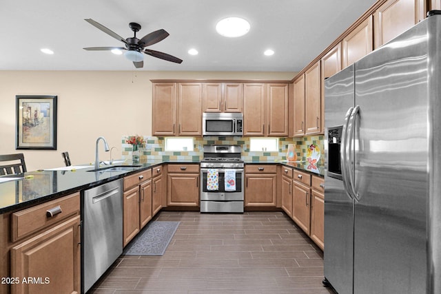 kitchen with appliances with stainless steel finishes, dark stone counters, a sink, and tasteful backsplash