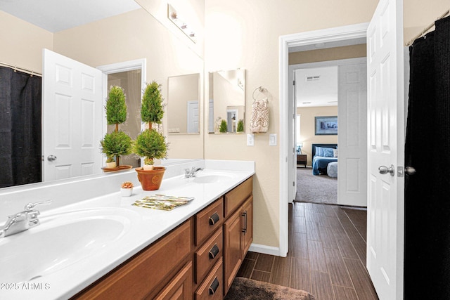 full bath with wood finish floors, a sink, baseboards, and double vanity