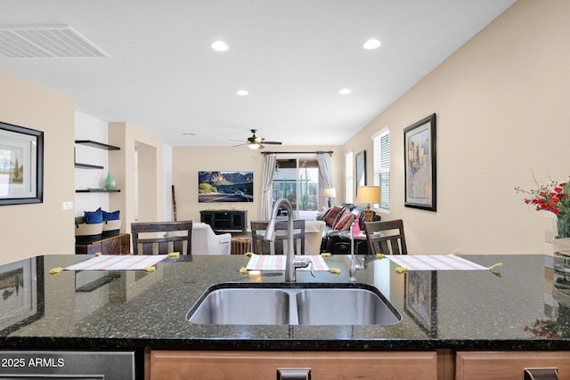 kitchen featuring open floor plan, dark stone counters, a sink, and visible vents