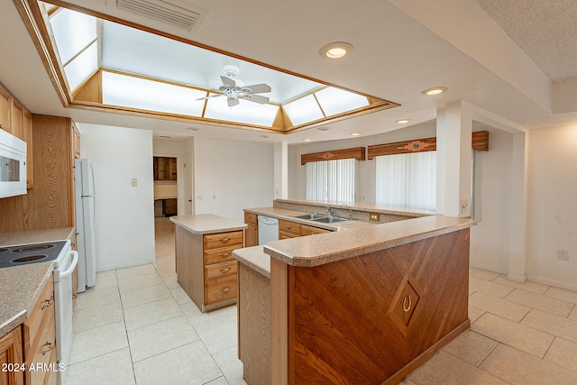 kitchen featuring white appliances, light tile patterned flooring, a skylight, a kitchen island, and kitchen peninsula