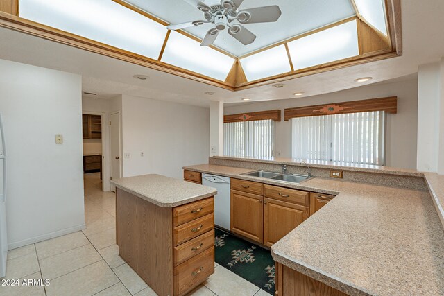 kitchen featuring light tile patterned flooring, dishwasher, sink, and a kitchen island