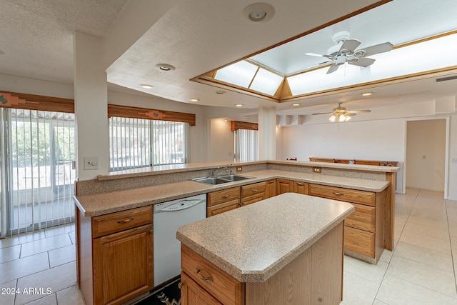 kitchen with kitchen peninsula, a kitchen island, a textured ceiling, white dishwasher, and sink