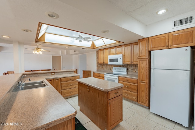 kitchen with a center island, light tile patterned floors, a skylight, white appliances, and ceiling fan