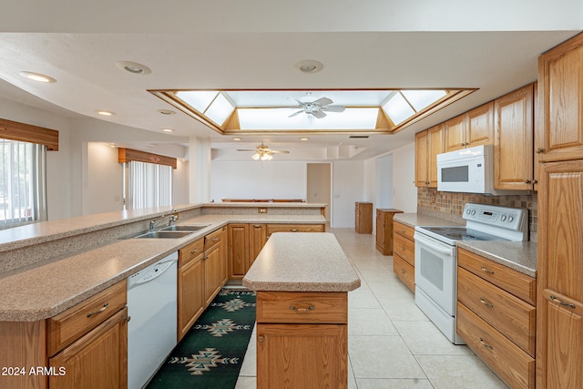 kitchen featuring a kitchen island, ceiling fan, white appliances, and a skylight