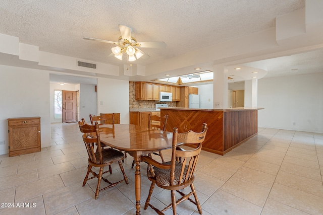 dining space with a textured ceiling, light tile patterned flooring, and ceiling fan