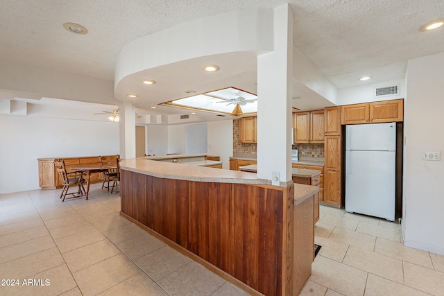 kitchen featuring kitchen peninsula, light tile patterned flooring, white refrigerator, and ceiling fan