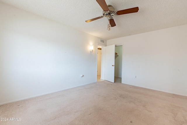 unfurnished room with a textured ceiling, light colored carpet, and ceiling fan