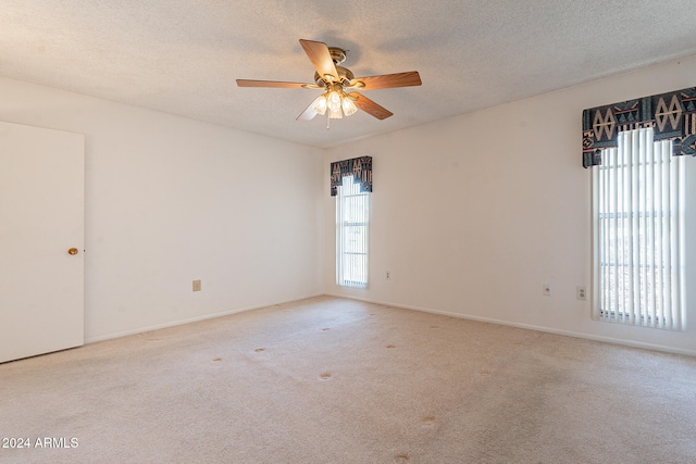 carpeted spare room with a textured ceiling, ceiling fan, and a wealth of natural light