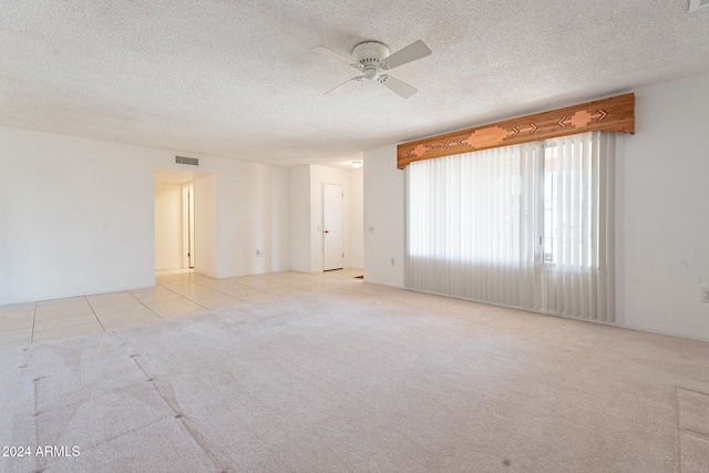 unfurnished room with a textured ceiling, light colored carpet, and ceiling fan