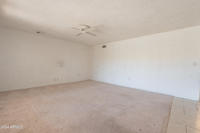 unfurnished room with a textured ceiling, light colored carpet, and ceiling fan