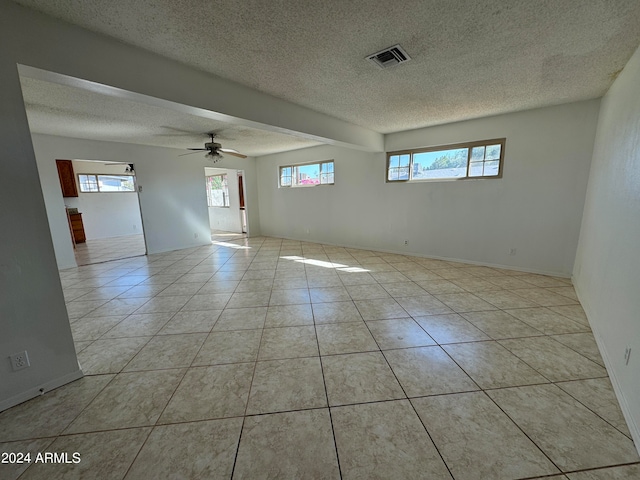 unfurnished room featuring ceiling fan, a healthy amount of sunlight, a textured ceiling, and light tile patterned floors