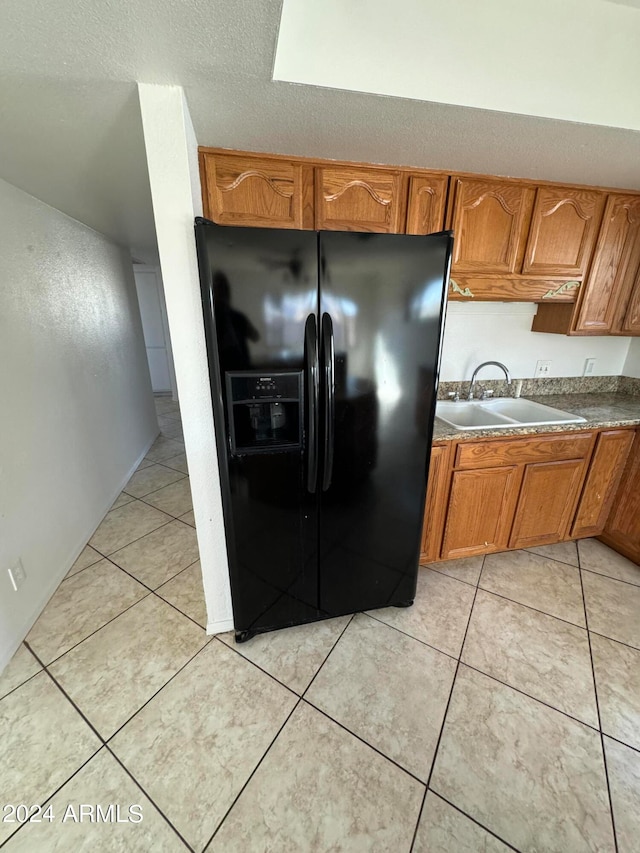 kitchen featuring sink, light tile patterned flooring, a textured ceiling, and black fridge with ice dispenser