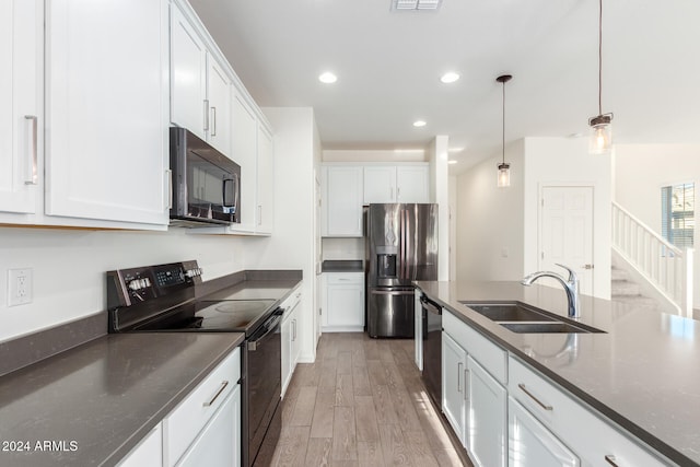 kitchen featuring black appliances, sink, hardwood / wood-style floors, hanging light fixtures, and white cabinets