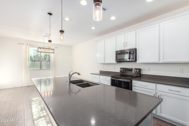 kitchen featuring white cabinets, a kitchen island with sink, sink, decorative light fixtures, and stainless steel appliances