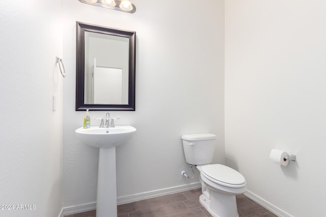 bathroom featuring toilet, wood-type flooring, and sink