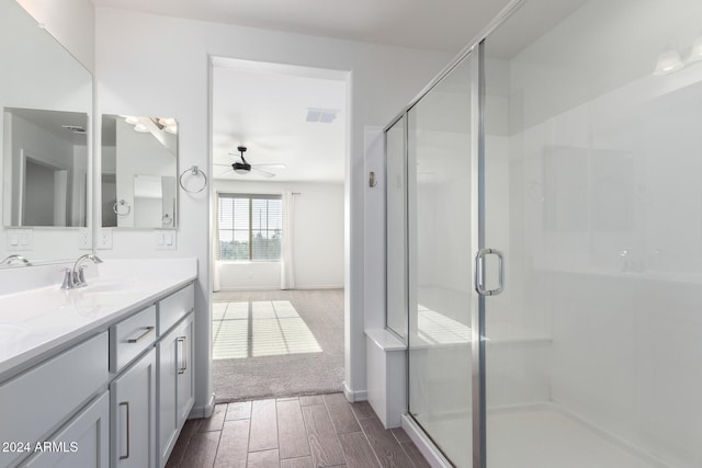 bathroom featuring vanity, hardwood / wood-style floors, a shower with shower door, and ceiling fan